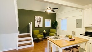 Una cocina moderna con armarios blancos, una mesa de comedor de madera y una escalera que lleva a otra habitación.