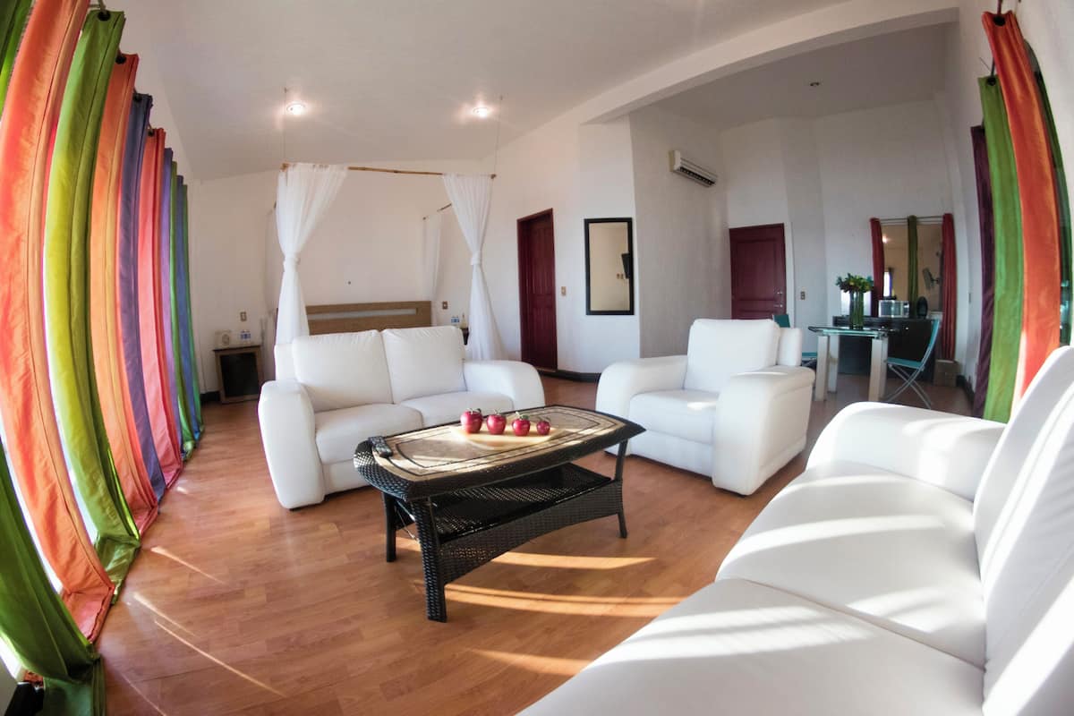 A modern living room with white sofas, a glass coffee table, and a wooden floor.