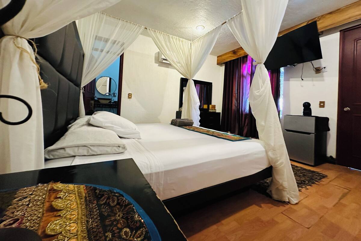 A bedroom with a bed, a bedside table, a mirror, and a wardrobe.