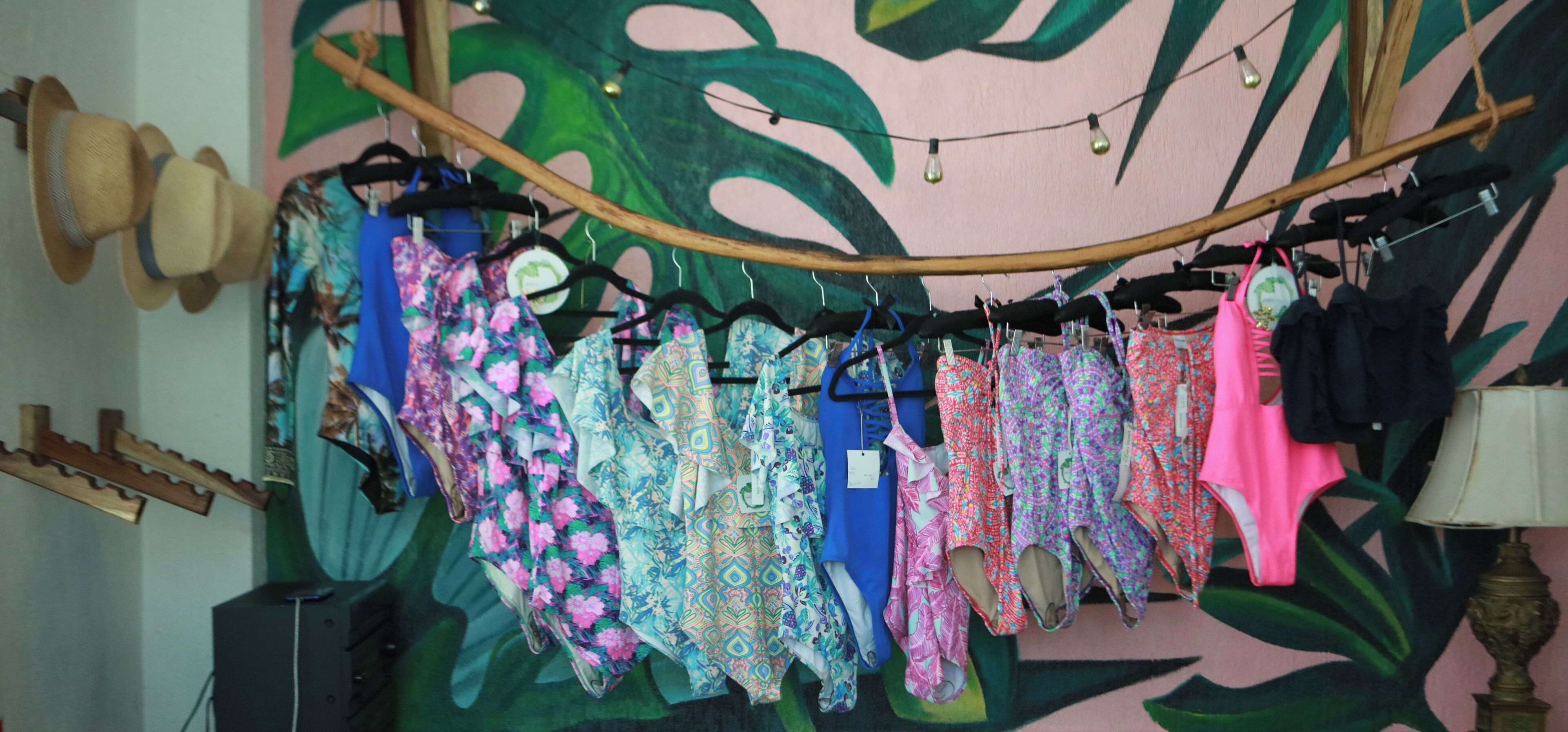 A clothing rack with various patterned dresses and a hat stand with hats.