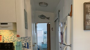 Una cocina pequeña con salpicadero de azulejos, una cafetera y un refrigerador.