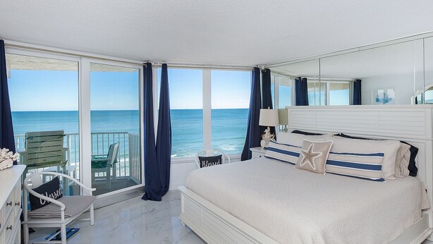 A bedroom with a large bed, a chair, and a view of the ocean. - WEEKLY SUMMER SPECIALS! Oceanfront Condo - Heated Pool - NO DRIVE BEACH (Daytona Beach Shores)