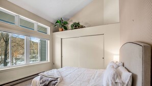 A bedroom with a bed, a window, a door, and a plant on the windowsill. - Loon Escape (Lincoln)