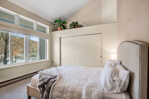 A bedroom with a bed, a window, a door, and a plant on the windowsill. - Loon Escape (Lincoln)