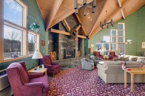 A cozy living room with a stone fireplace, wooden beams, and large windows. - Loon Escape (Lincoln)