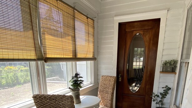 Una habitación acogedora con una puerta de madera, una mesa redonda con sillas y una pequeña planta en maceta.