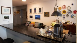 Een moderne keuken met een granieten aanrecht, een koffiezetapparaat en diverse decoratieve borden aan de wand.