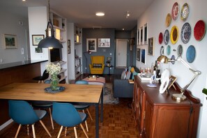 A dining area with a wooden table, blue chairs, and a vase with flowers.