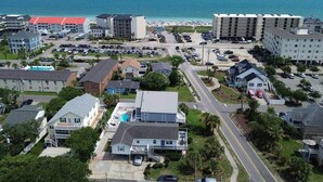 A coastal residential area with multiple buildings, a beach, and a parking lot.