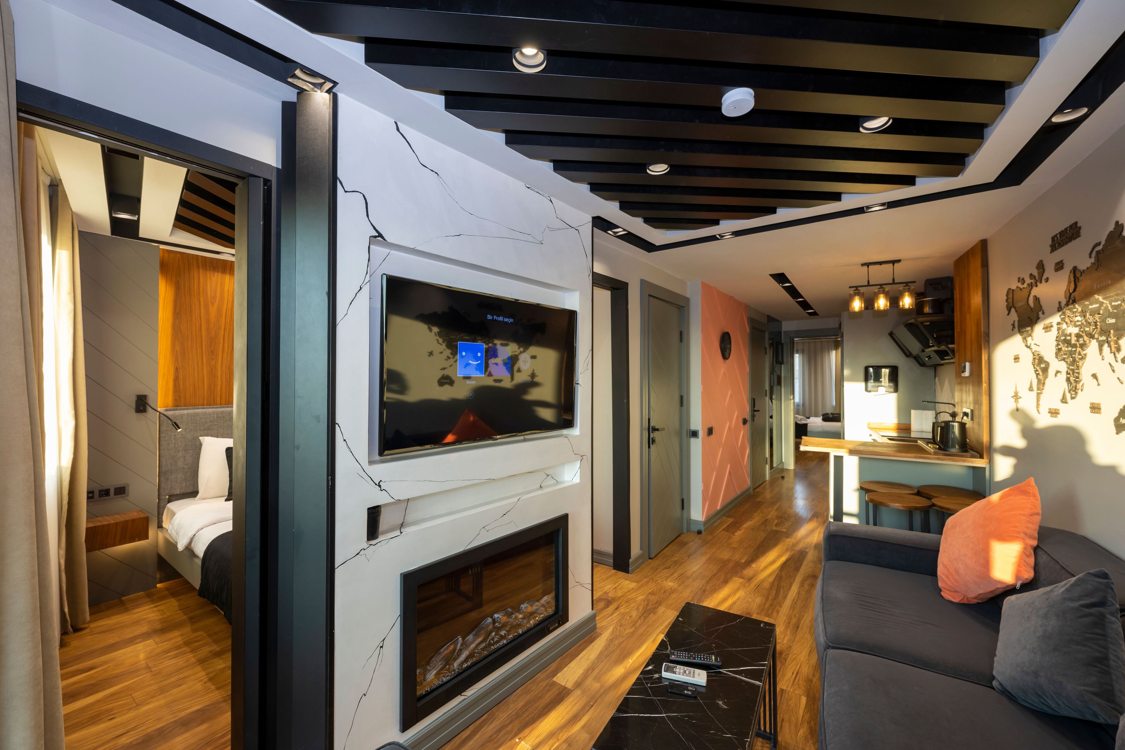 A modern living room with a fireplace, a TV mounted on the wall, and a sofa with cushions.