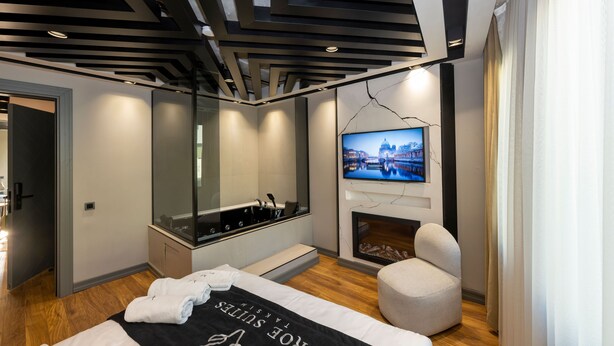 Ein modernes Hotelzimmer mit Bett, Sitzecke, Fernseher und Kamin.