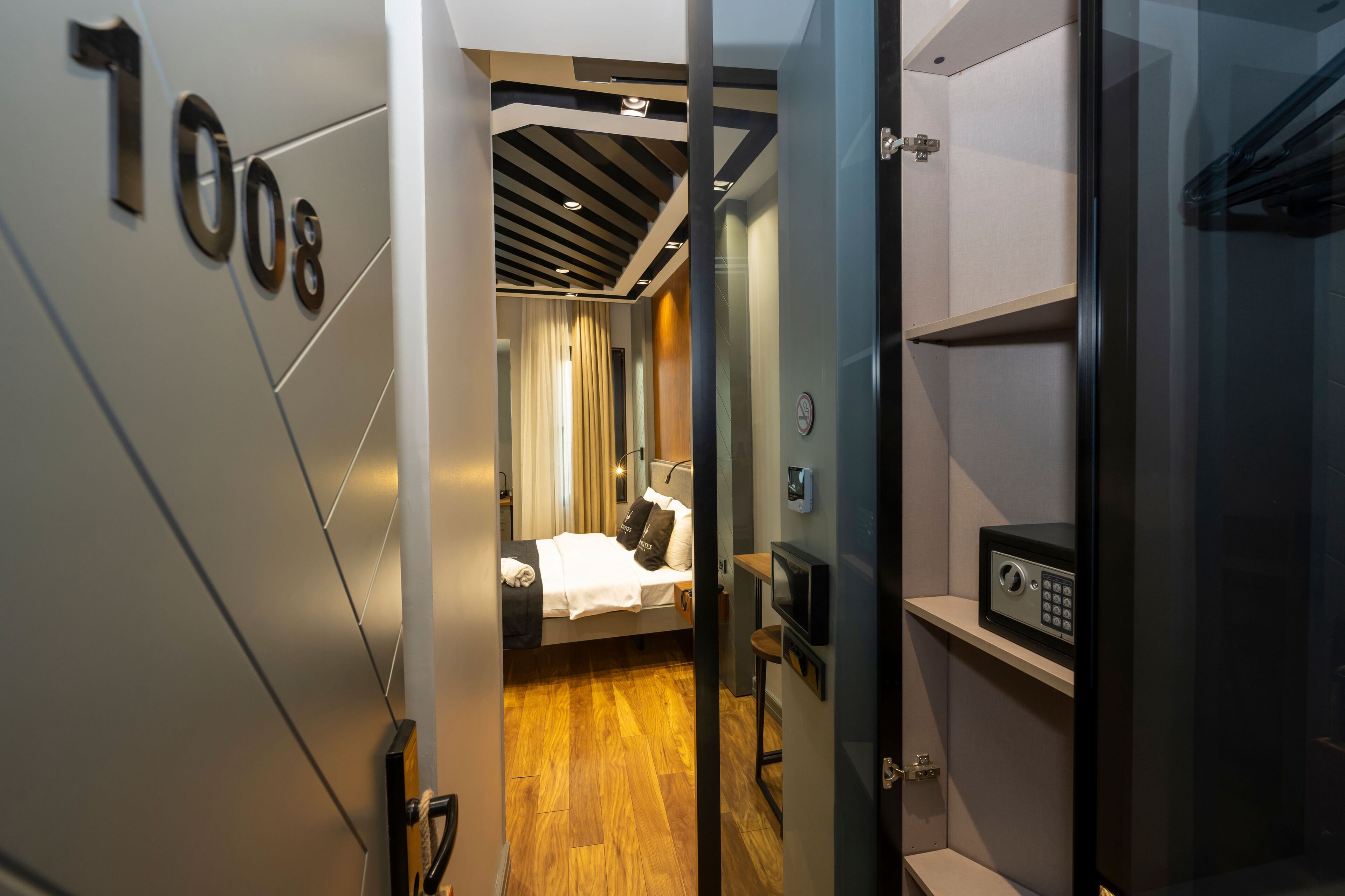 Ein Hotelzimmer mit Bett, Schreibtisch, Safe und Blick auf den Flur.