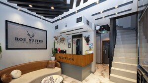Ein Hotel-Empfangsbereich mit einer Rezeption, einer Couch, einem Couchtisch und einer Treppe.
