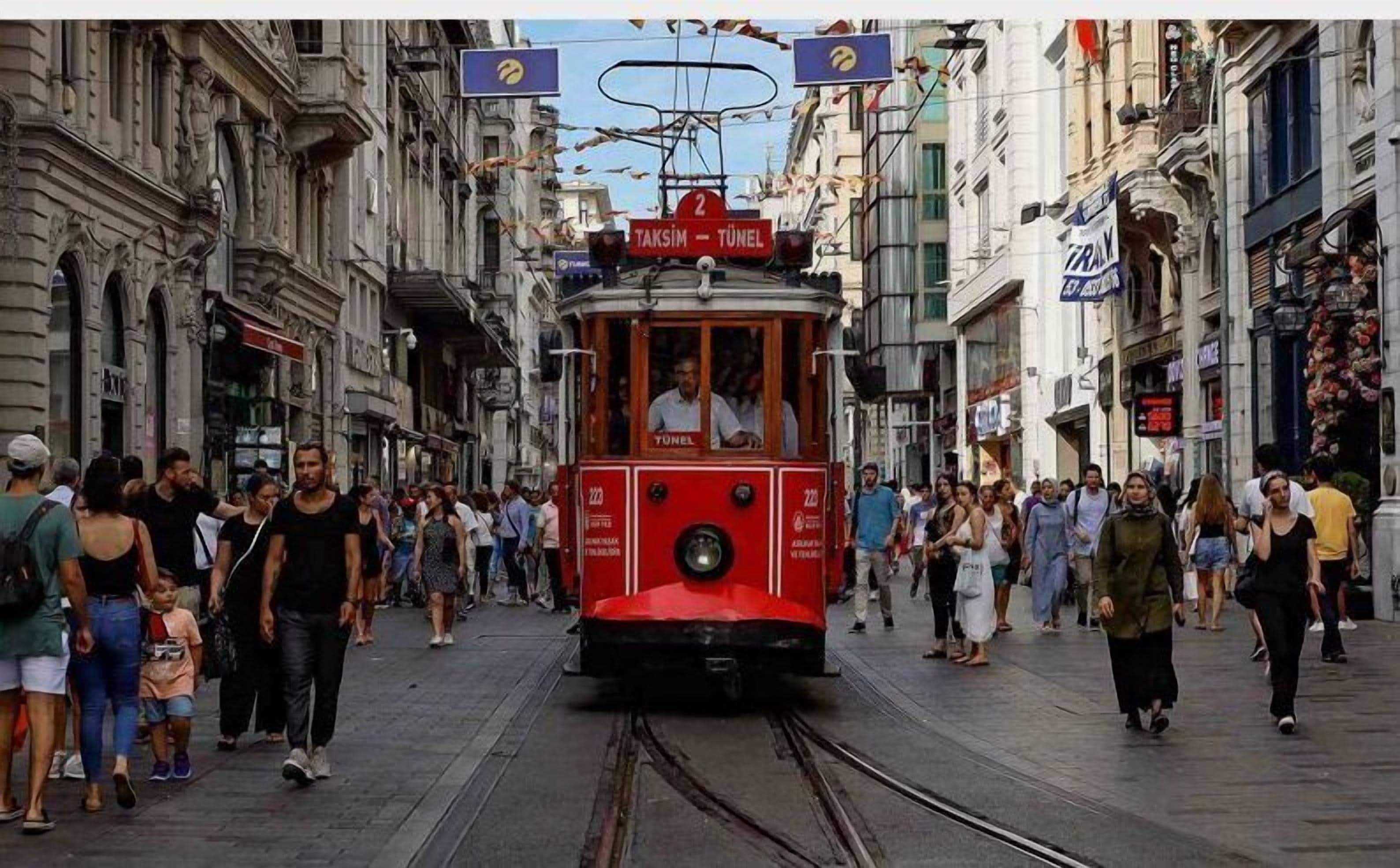 A red tram with the number 2 on a street with pedestrians.