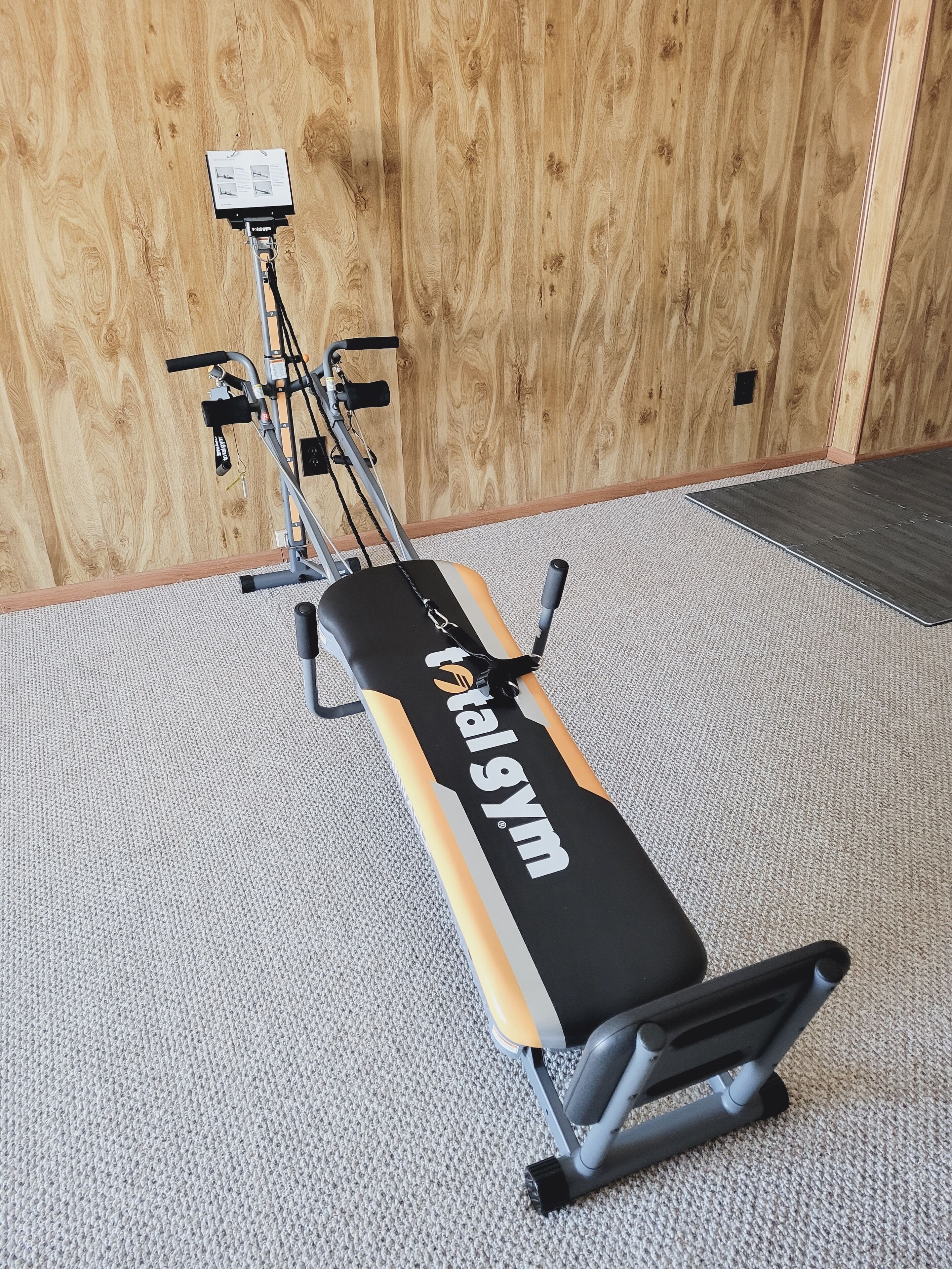 A gym with a bench and exercise equipment against a wooden wall.