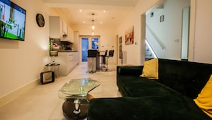 Una sala de estar moderna con un sofá verde, una mesa de centro de cristal y un televisor montado en la pared.