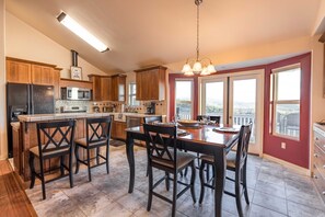 A kitchen with wooden cabinets, a stainless steel refrigerator, a microwave, and a dining area with a table and chairs.