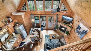A cabin with a loft bedroom, a dining area, a kitchen, and a living room.