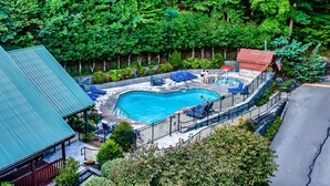 An aerial view of a resort with a swimming pool, lounge chairs, and a fenced deck area.