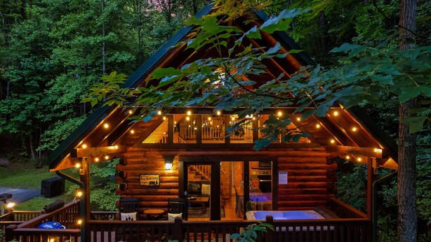 A log cabin with a deck, a hot tub, and a sign indicating it is a lodge.