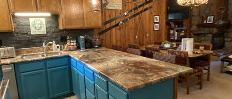 Una cocina con armarios azules, encimera de granito y chimenea de piedra.