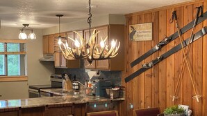 Een keuken met houten wanden, een centraal eiland en een kroonluchter met gewei details.
