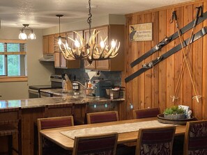 Une cuisine aux murs en bois, dotée d’un îlot central et d’un lustre orné de motifs de bois de cerf.