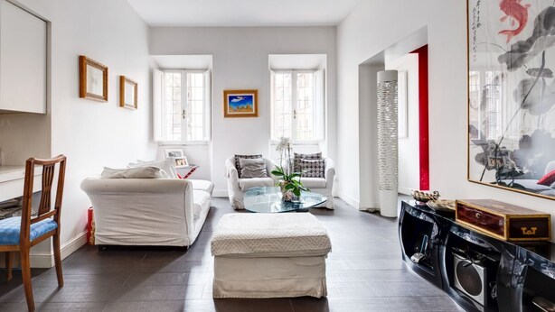 Ein modernes Wohnzimmer mit einer Couch, Hocker, Couchtisch, einem Sessel und einem Kamin.