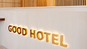 A reception area with a sign that reads "GOOD HOTEL" and a logo above it.
