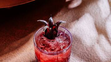 Un vaso de bebida roja con un adorno decorativo sobre una superficie texturizada.