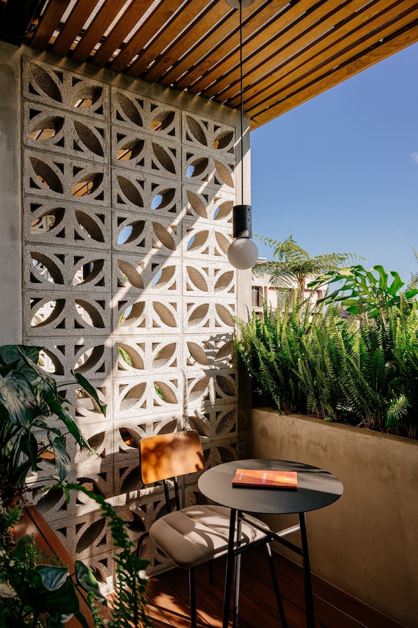 A patio with a wooden ceiling, a decorative concrete wall, and a round table with a chair.