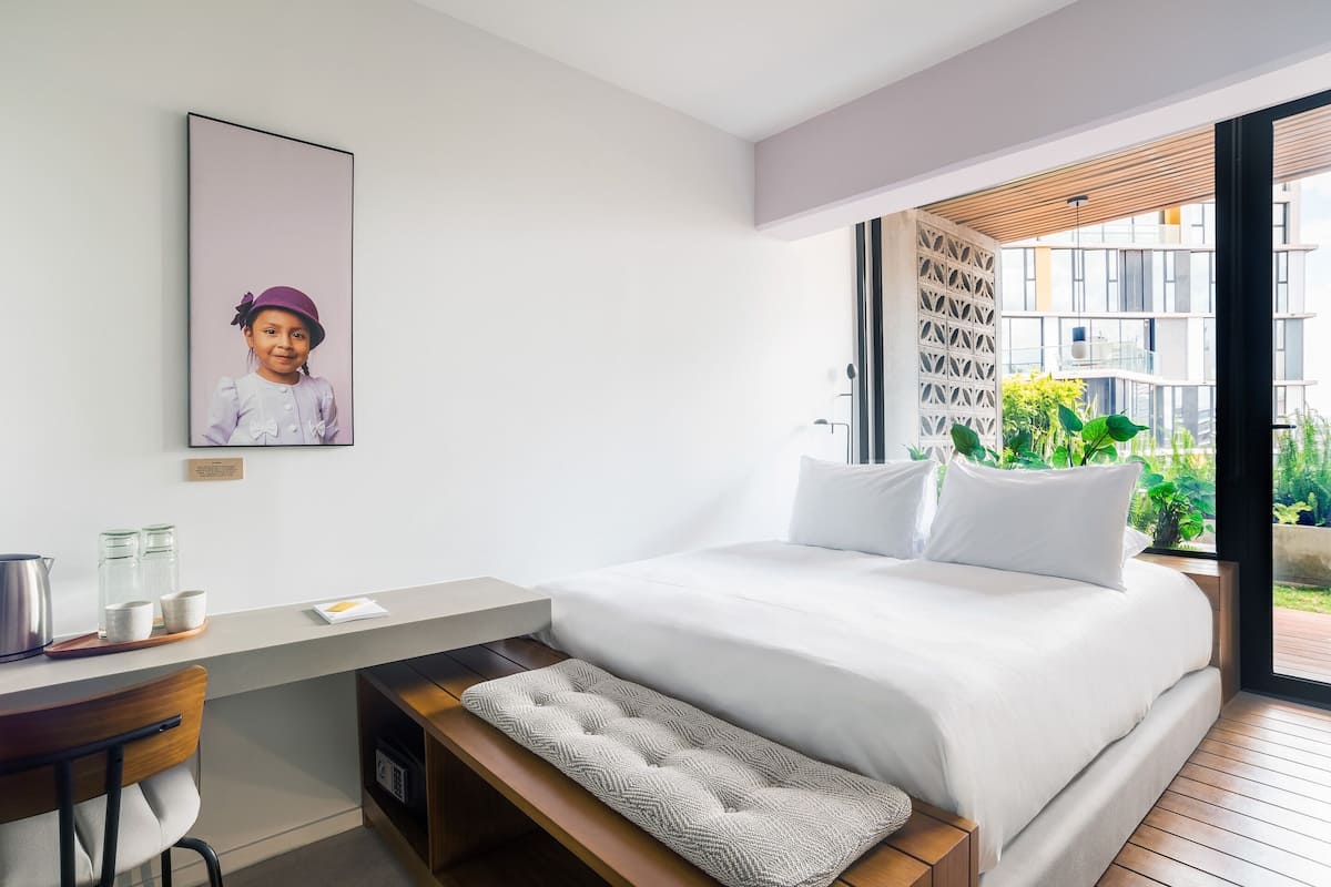 A modern bedroom with a large bed, a desk, and a bench.