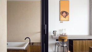 A modern bathroom with a bathtub, a wooden vanity, and a wall-mounted mirror.