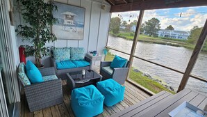 Eine Terrasse mit Korbmöbeln und blauen Kissen mit Blick auf einen Fluss.