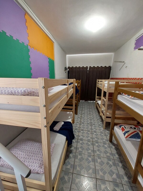 Un dormitorio con literas, piso de baldosas y pared de colores.