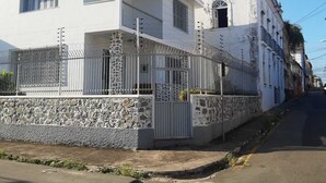 Un edificio blanco con base de piedra y cerca de metal.