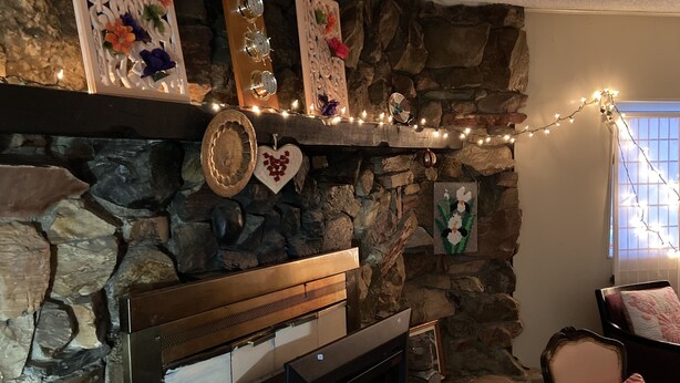 Una chimenea de piedra con televisor, adornos y luces colgantes.