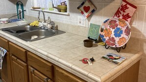 Una cocina con armarios de madera, un lavamanos y una ventana con cortina.