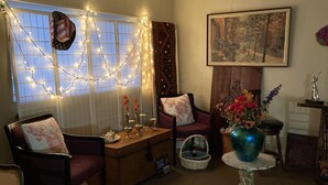 Una sala de estar acogedora con chimenea, un ventanal con cortinas, una mesa de comedor con sillas y un jarrón decorativo.