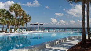 Ein Pool mit Liegestühlen und Palmen, eine Pergola und Meerblick.