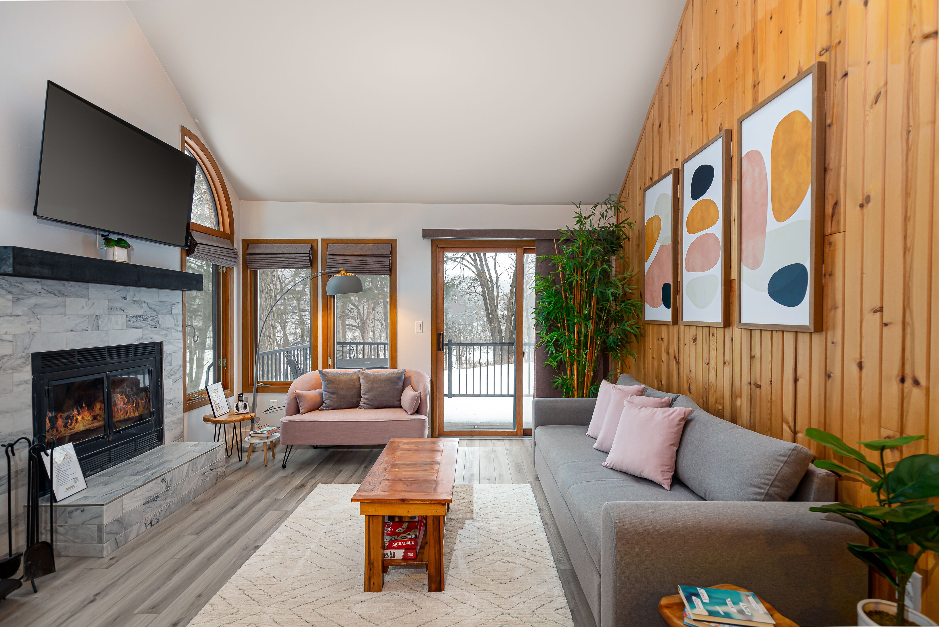 A living room with a fireplace, two sofas, a coffee table, and a TV mounted on the wall.