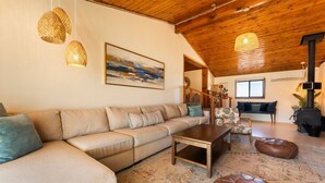A cozy living room with a sofa, a coffee table, and a patterned rug. - The Magic Hour House | Spa | Pool | Games | Cozy (Joshua Tree)