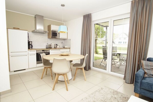 A modern kitchen with a dining area, a large window with curtains, and a view of the outdoors. - Beachfront apartment with terrace, use of swimming pool and sauna - Rex Rugia - Rex (Göhren)