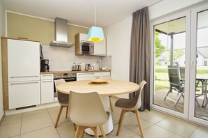 A modern kitchen with a round table, chairs, and a dining area with a view of the outdoors. - Beachfront apartment with a terrace, pool, and sauna - Rex Rugia - Rex (Göhren)