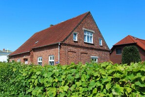 A two-story brick house with a red-tiled roof, surrounded by lush green foliage. - F-1009 Sonnenhut - Ferienwohnung Sonnenhut F-1009 (Baabe)