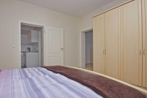A bedroom with a bed, a wardrobe, and a door leading to a bathroom.