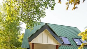 Een tweelaags huis met een groen dak, een voortuin en een trap die naar de ingang leidt.