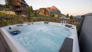 Een hottub op een terras met uitzicht op bergen.