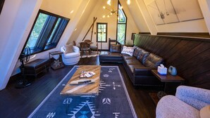 Een knus loft-woonkamer met een groot raam, een bank, een salontafel en een open haard.