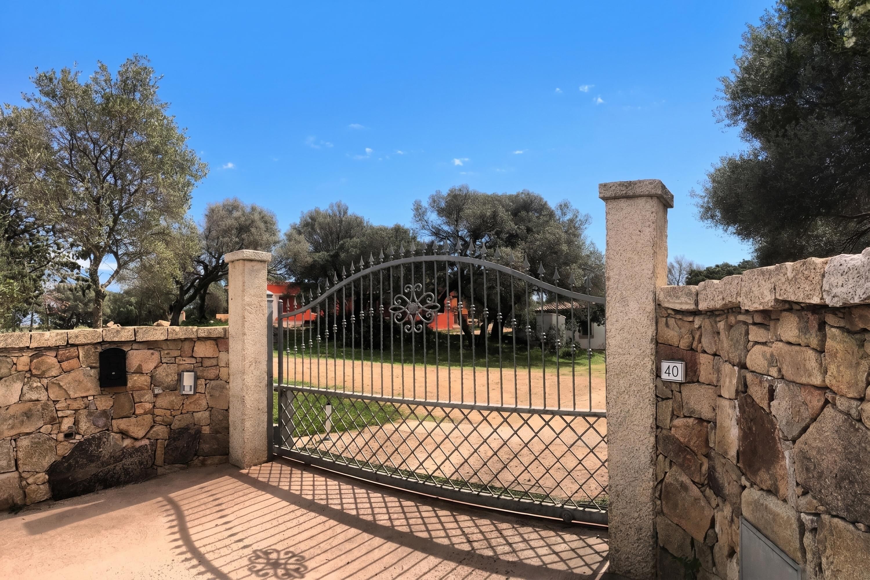 A gated entrance with a stone wall, a metal gate, and a number sign indicating the location.